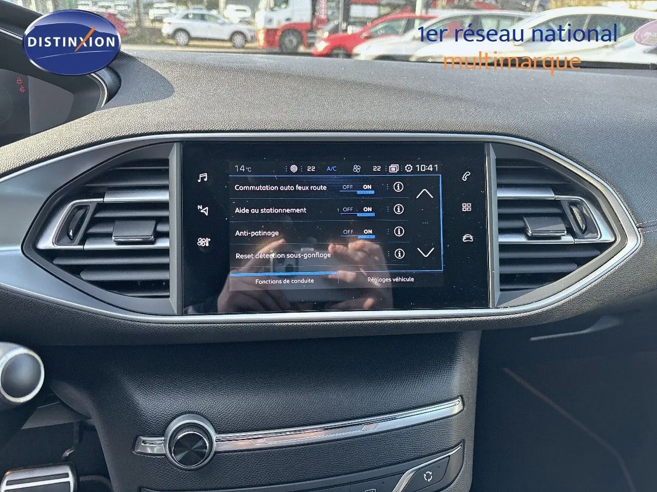 Tableau de bord de Peugeot 308 blanc nacré, écran tactile central affichant les réglages d'aide à la conduite.