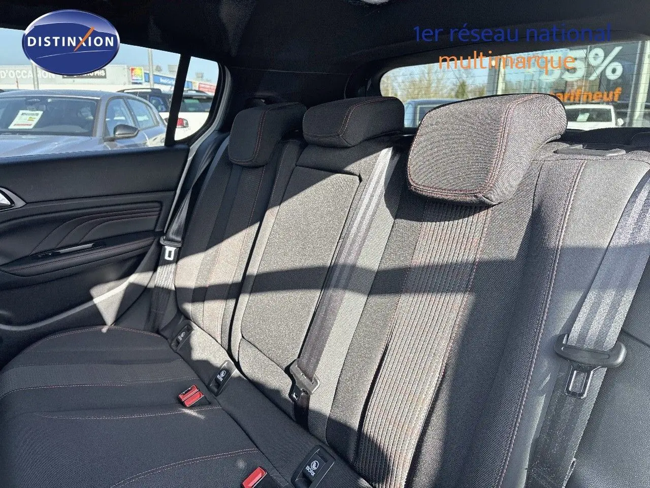 Vue latérale intérieure montrant la banquette arrière en tissu gris avec surpiqûres rouges du Peugeot 308 blanc nacré 2021.