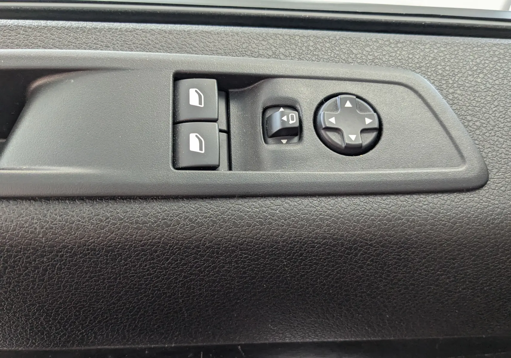 Gros plan sur les commandes noires des vitres et rétroviseurs sur la portière intérieure du Peugeot Expert Fourgon blanc 2024.