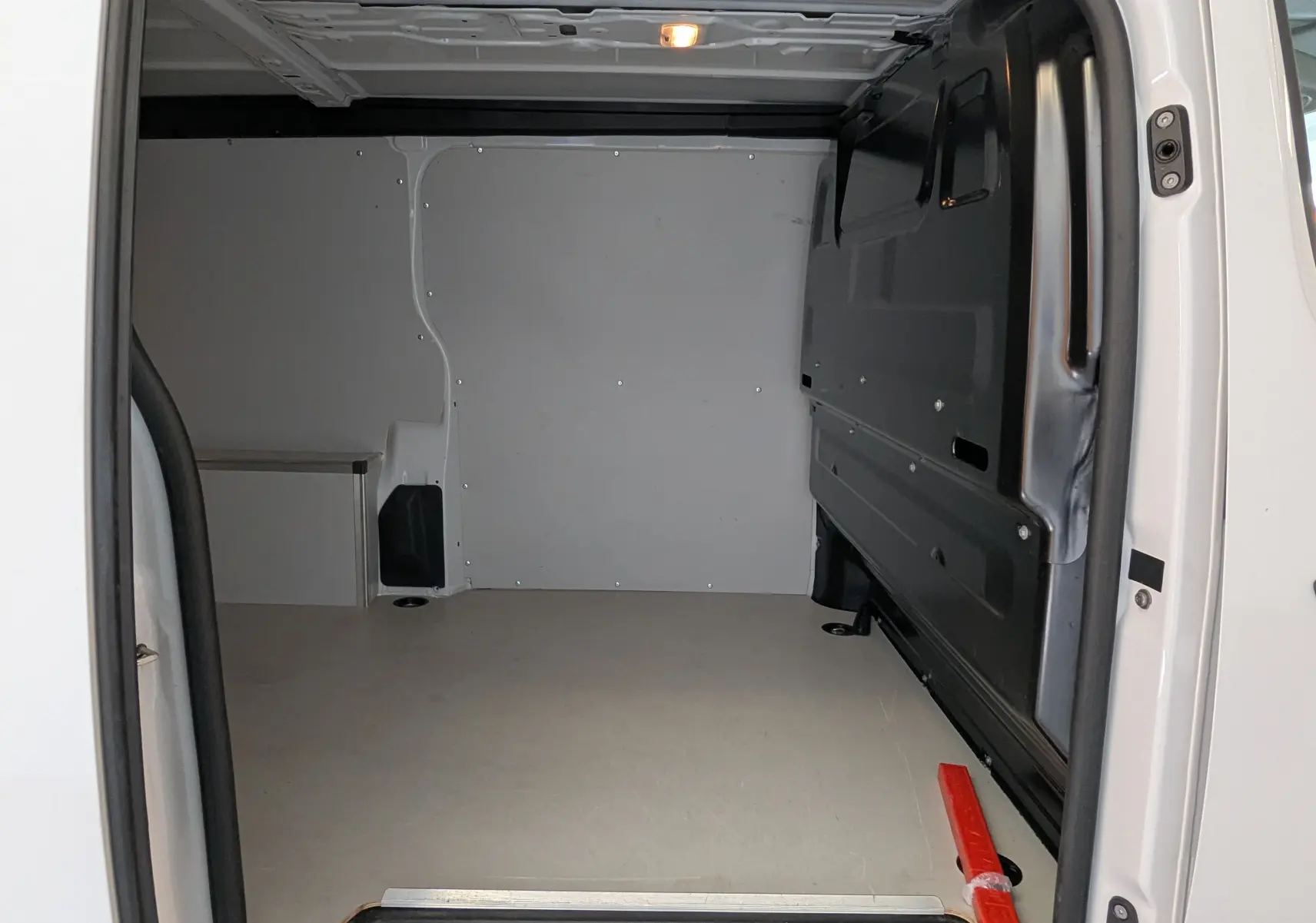 Vue intérieure arrière du Peugeot Expert Fourgon blanc 2024, montrant l'espace de chargement avec plancher bois et côtés antidérapants.