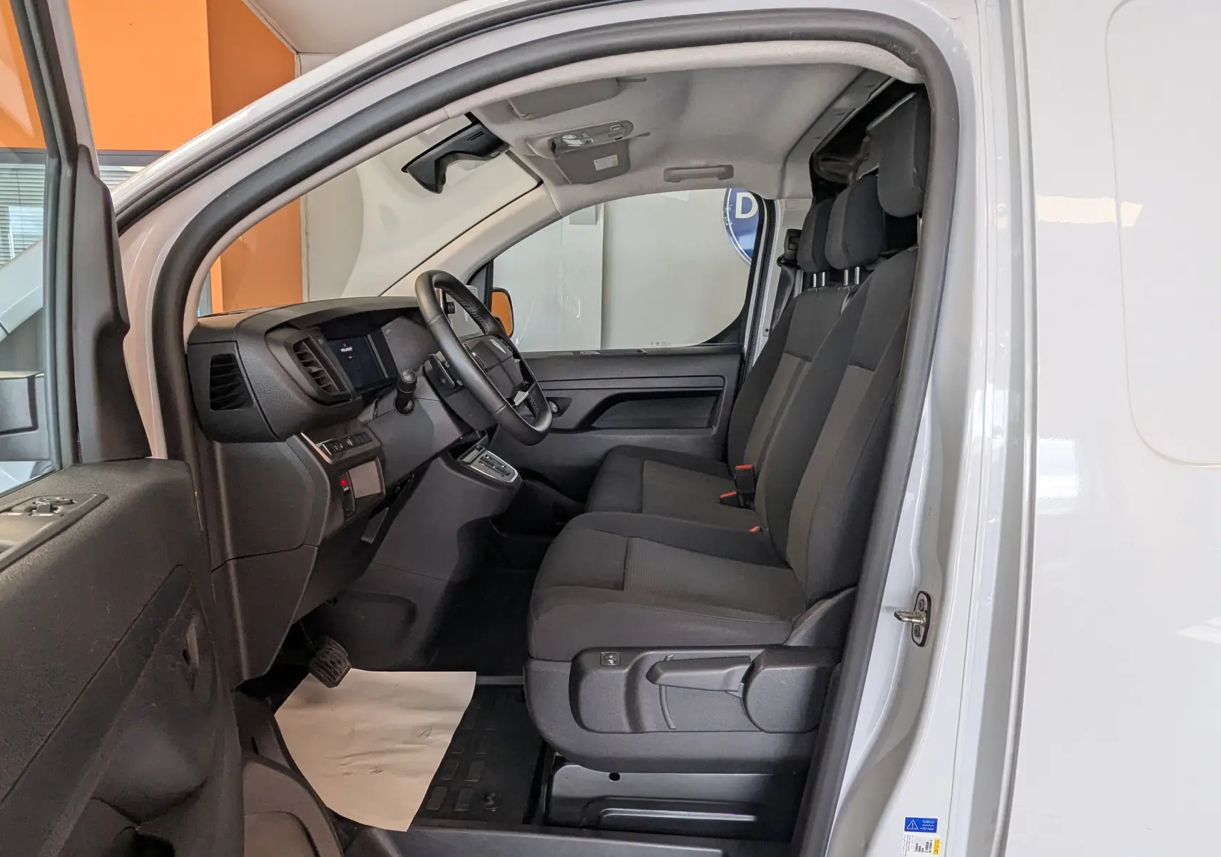 Intérieur du Peugeot Expert Fourgon blanc 2024, vue côté gauche sur les sièges avant noirs et le tableau de bord.