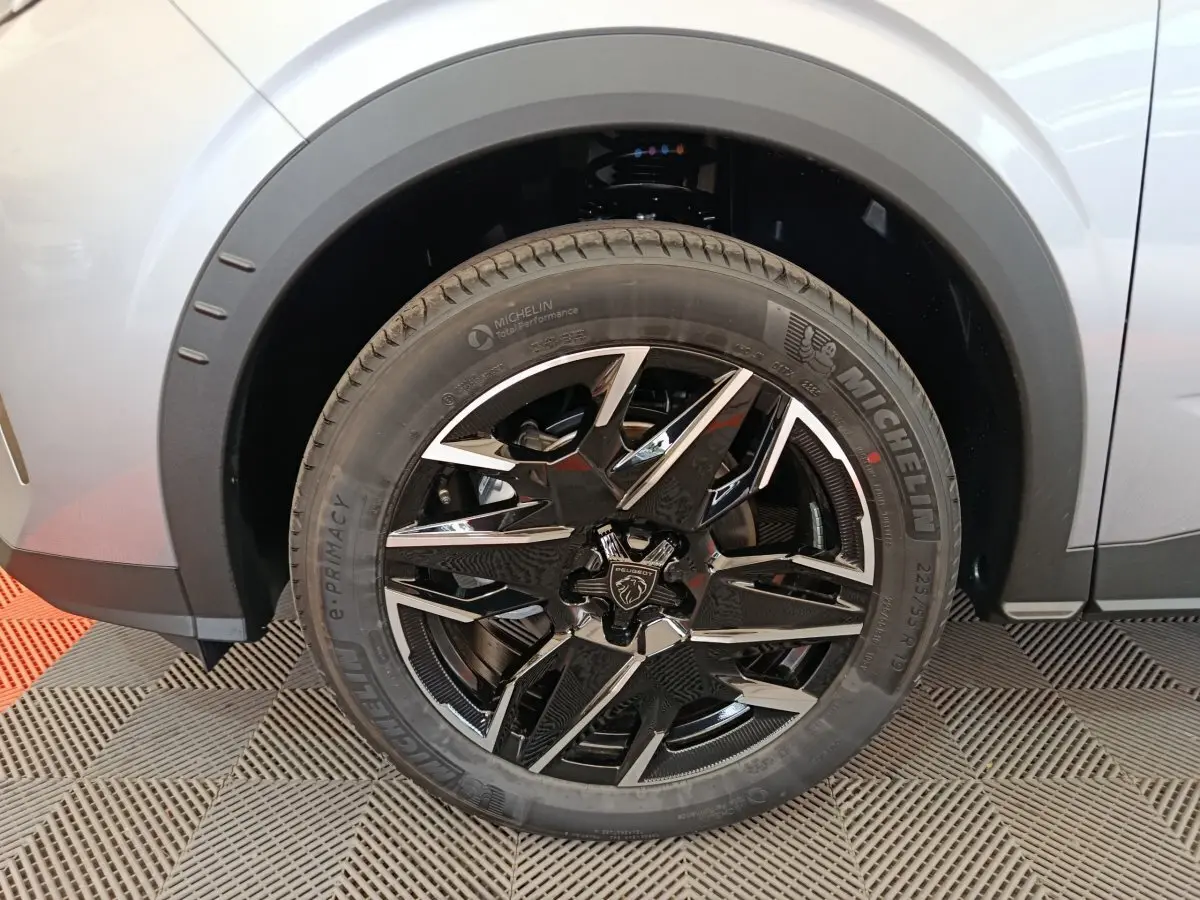 Gros plan sur la jante noire et argentée du côté avant droit d’un Peugeot 3008 gris clair hybride 2025.