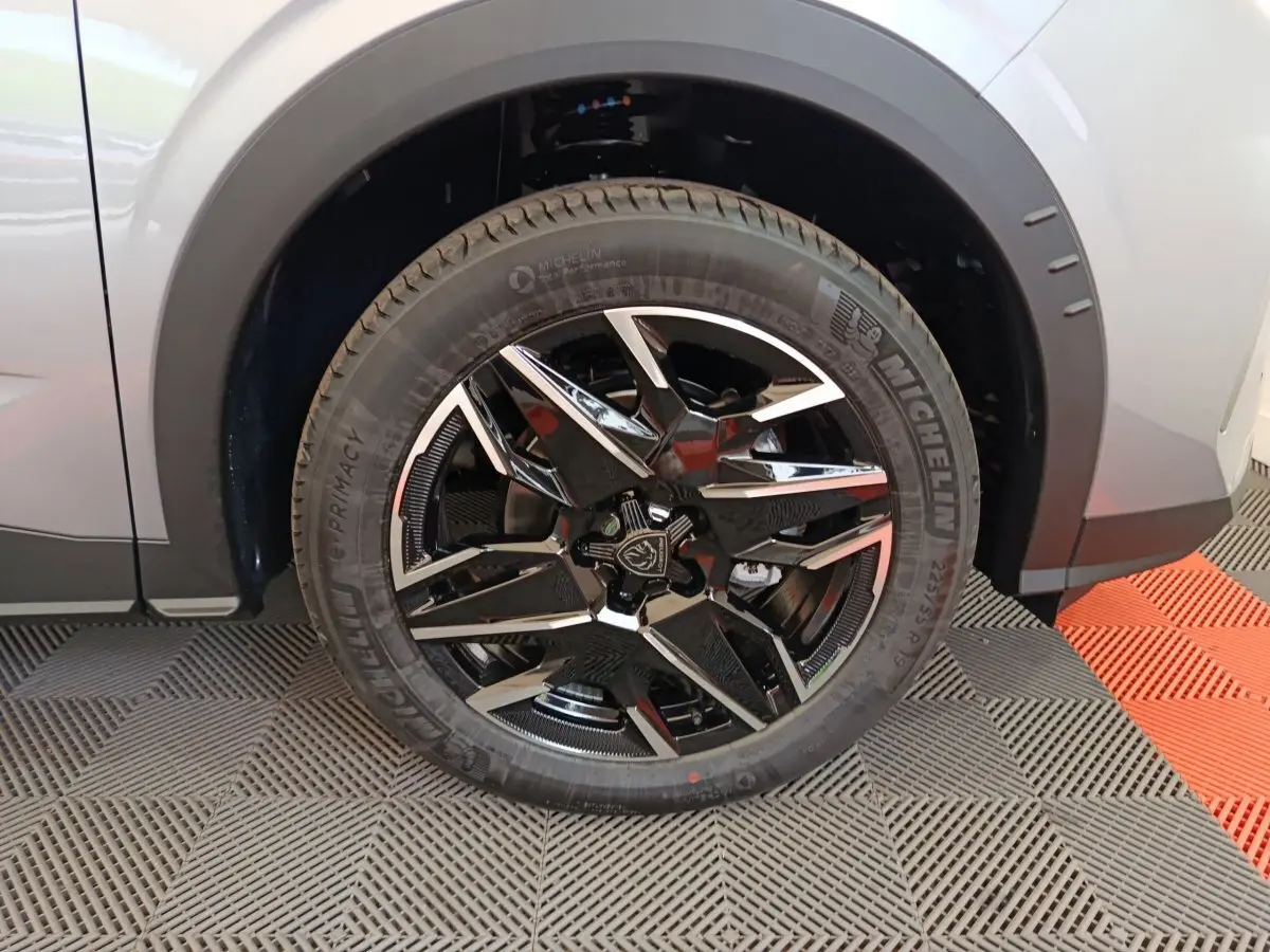 Gros plan sur la roue avant gauche du Peugeot 3008 gris clair, avec jante noire et argentée au design moderne.