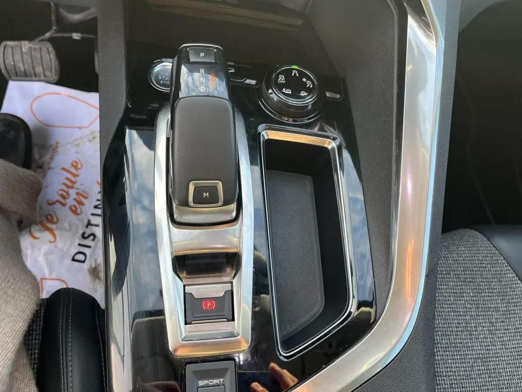 Gros plan sur la console centrale noire brillante du Peugeot 3008 2020 avec levier de boîte auto et bouton sport.