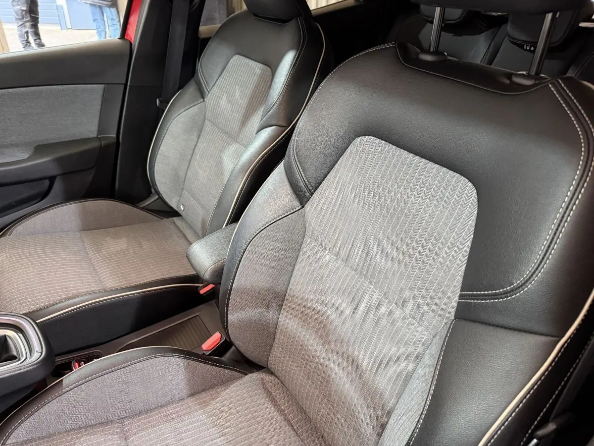 Gros plan sur les sièges avant gris et noirs de la Renault Clio Techno TCe 90 2024 avec surpiqûres blanches.