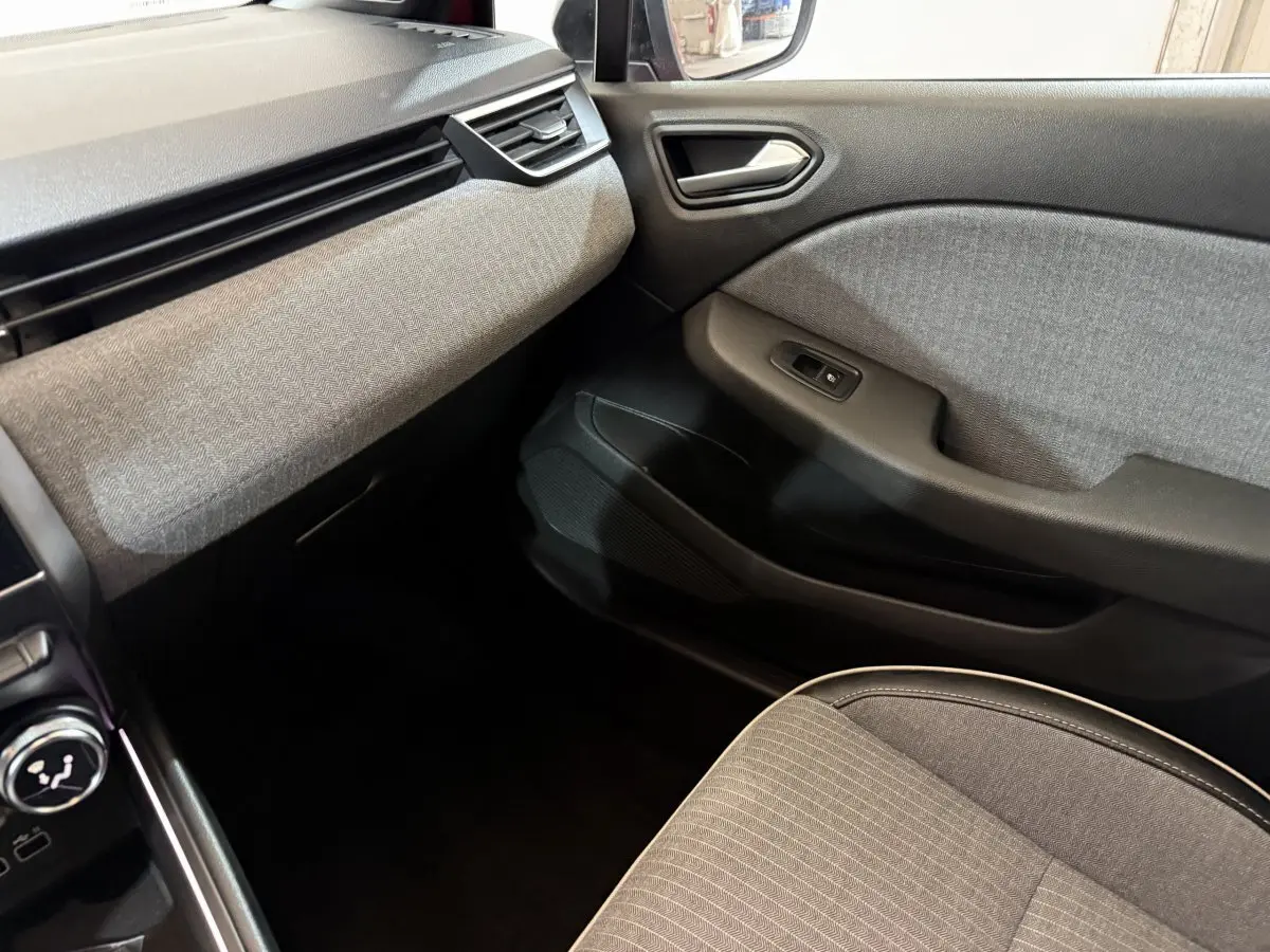 Vue intérieure côté passager de la Renault Clio Techno TCe 90 2024, avec tissu gris et détails noirs sur la porte et siège.