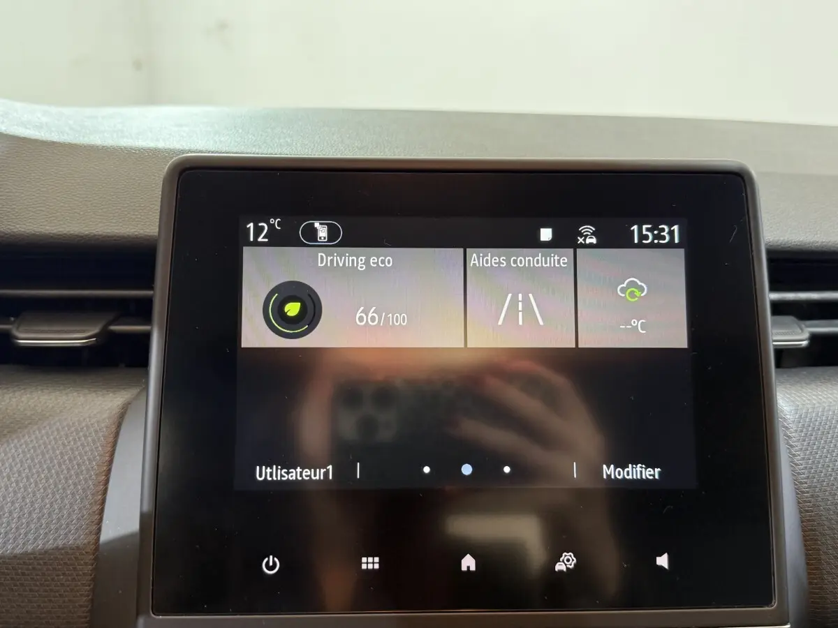 Écran tactile central de la Renault Clio Business blanc, affichant les aides à la conduite et la température extérieure.