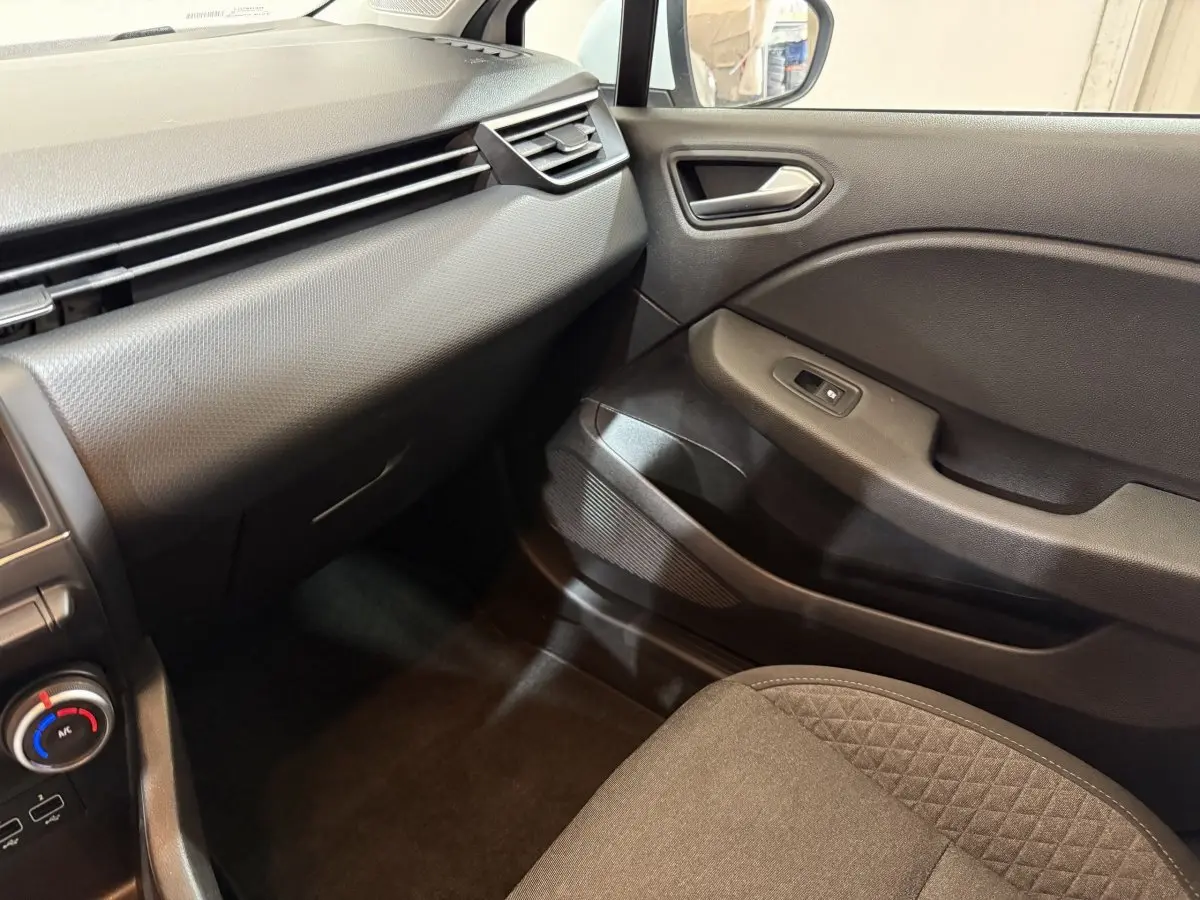Vue intérieure côté passager avant de la Renault Clio Business SCe 65 2021, montrant la portière et la console en plastique noir.
