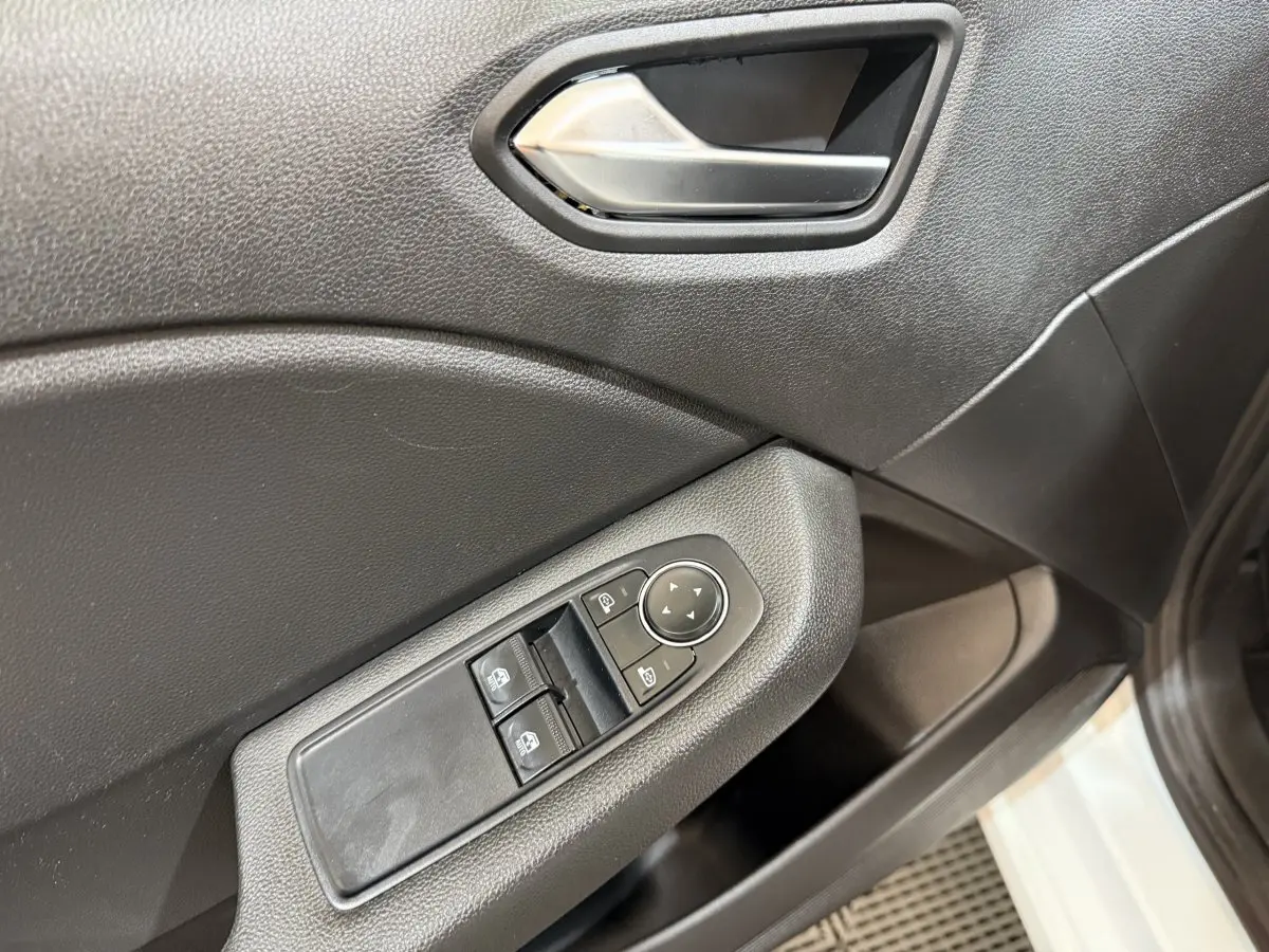 Vue rapprochée de la porte côté conducteur d'une Renault Clio blanche 2021, avec commandes électriques des vitres et rétroviseurs.
