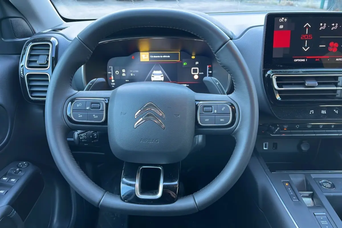 Vue centrée sur le volant cuir multifonctions et le tableau de bord numérique du Citroën C5 Aircross Hybrid blanc.