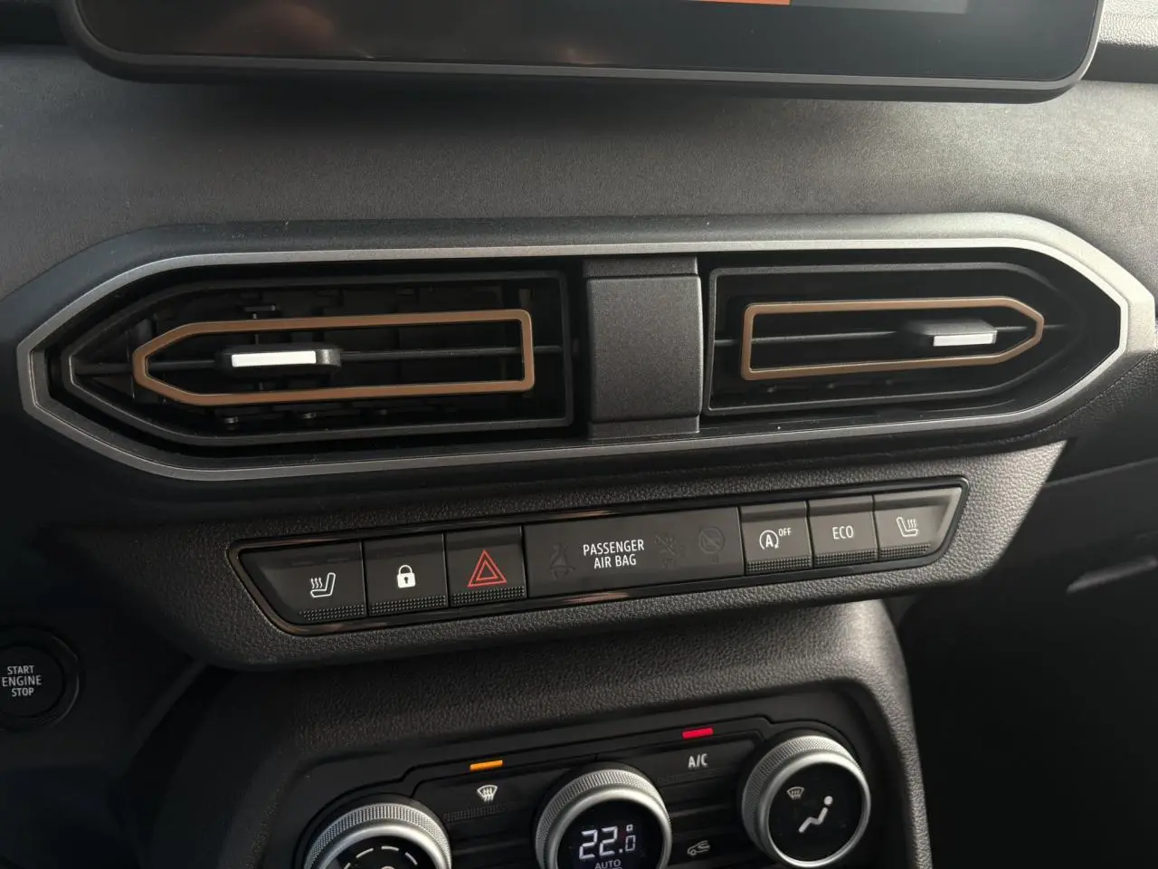 Détail du tableau de bord du Dacia Jogger gris urbain, avec commandes de climatisation et boutons fonctionnels visibles.