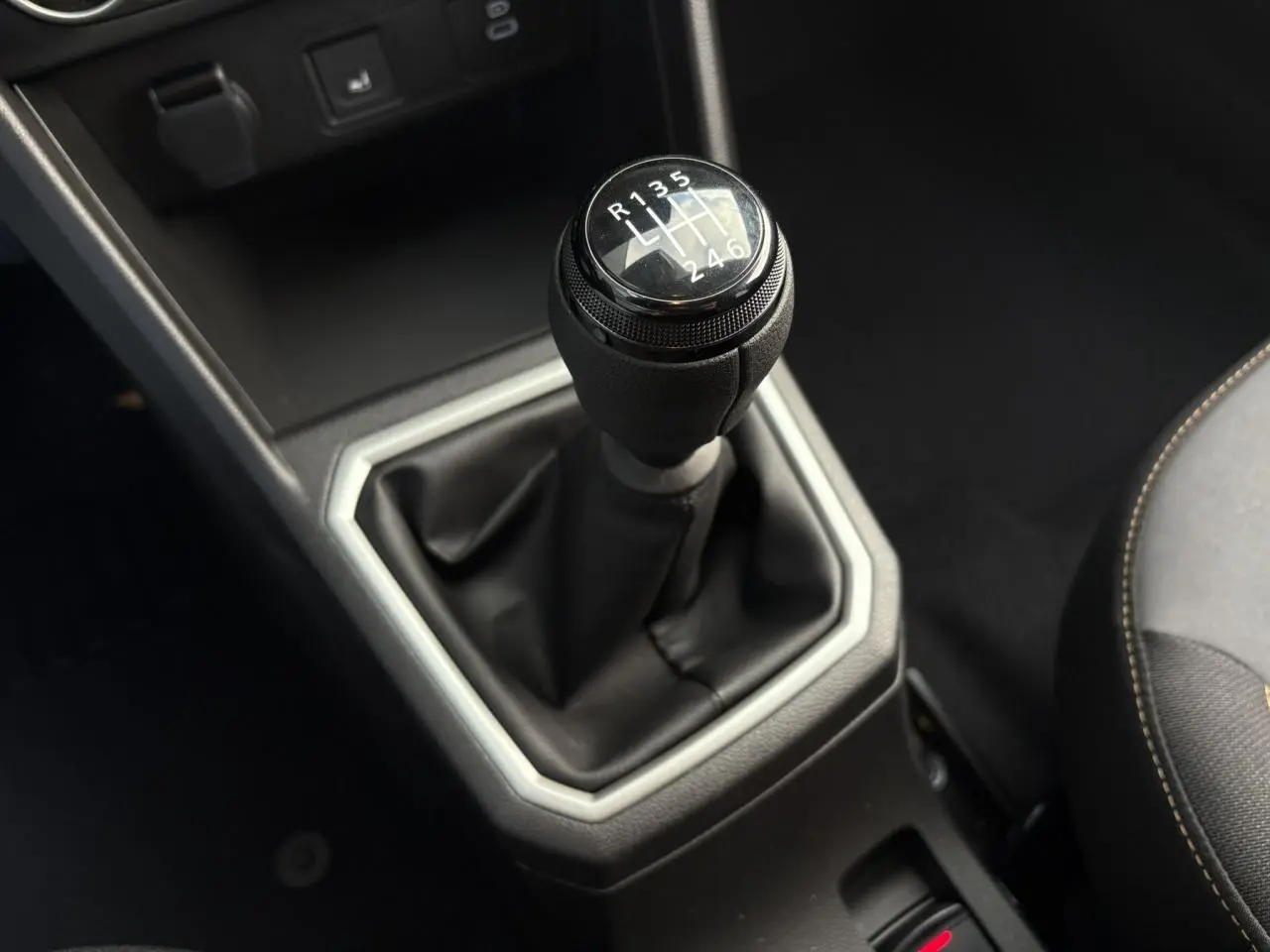 Le levier de vitesses manuel noir de la Dacia Jogger 2024 vu en gros plan depuis l'intérieur côté conducteur.
