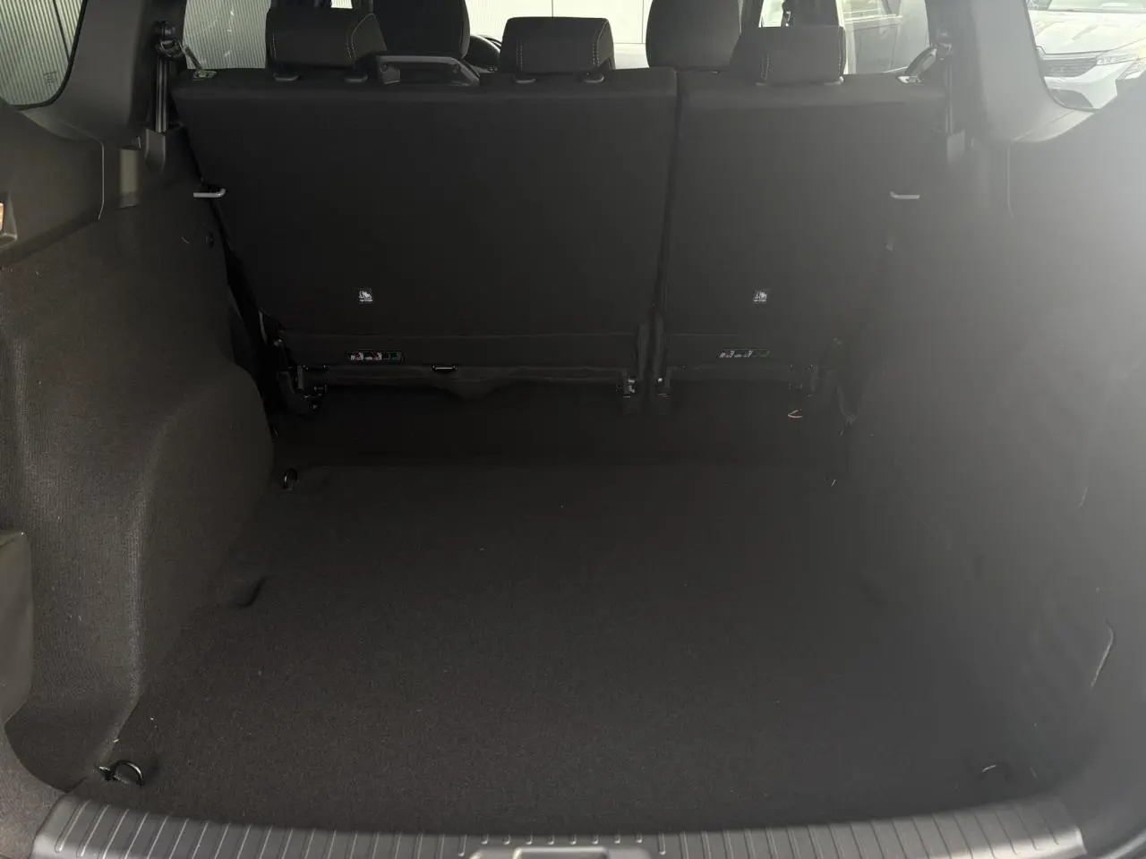 Coffre spacieux du Dacia Jogger Gris Urbain vu de l'arrière avec sièges arrière relevés et intérieur sombre.