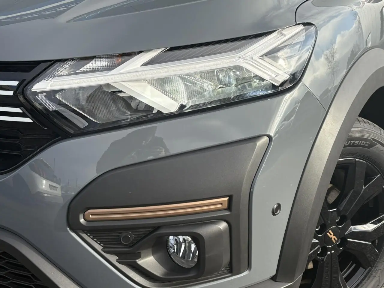 Gros plan sur le phare avant droit gris urbain du Dacia Jogger 2024 avec antibrouillard et jante noire distinctive.