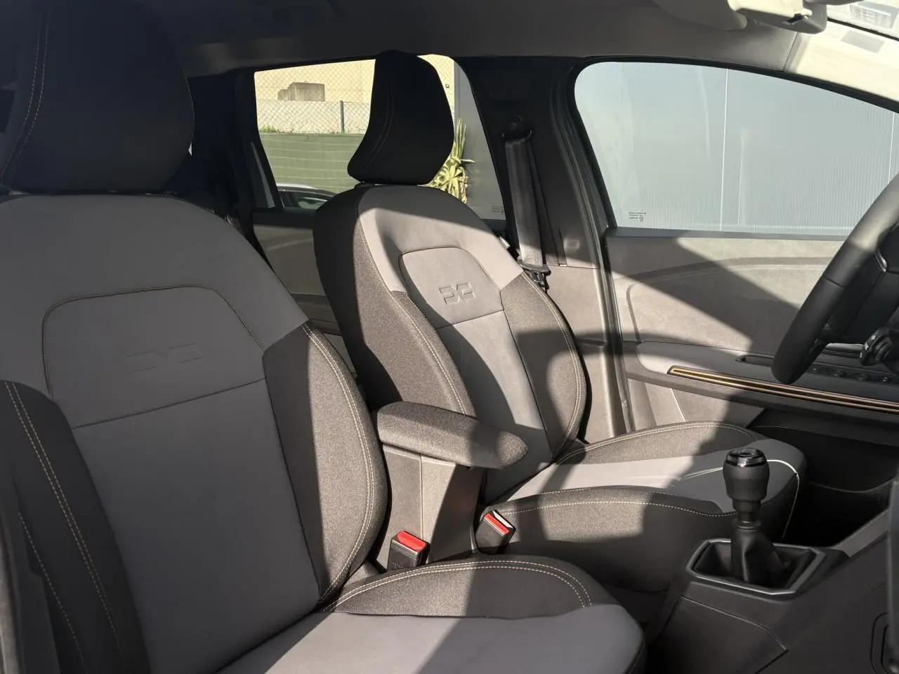Vue intérieure côté droit des sièges avant gris clair et foncé du Dacia Jogger ECO-G 100 Extreme+ avec accoudoir et levier de vitesse manuel.