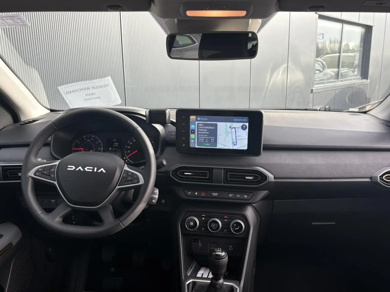 Vue intérieure frontale du tableau de bord du Dacia Jogger 2024 avec écran tactile GPS et volant multifonction noir.