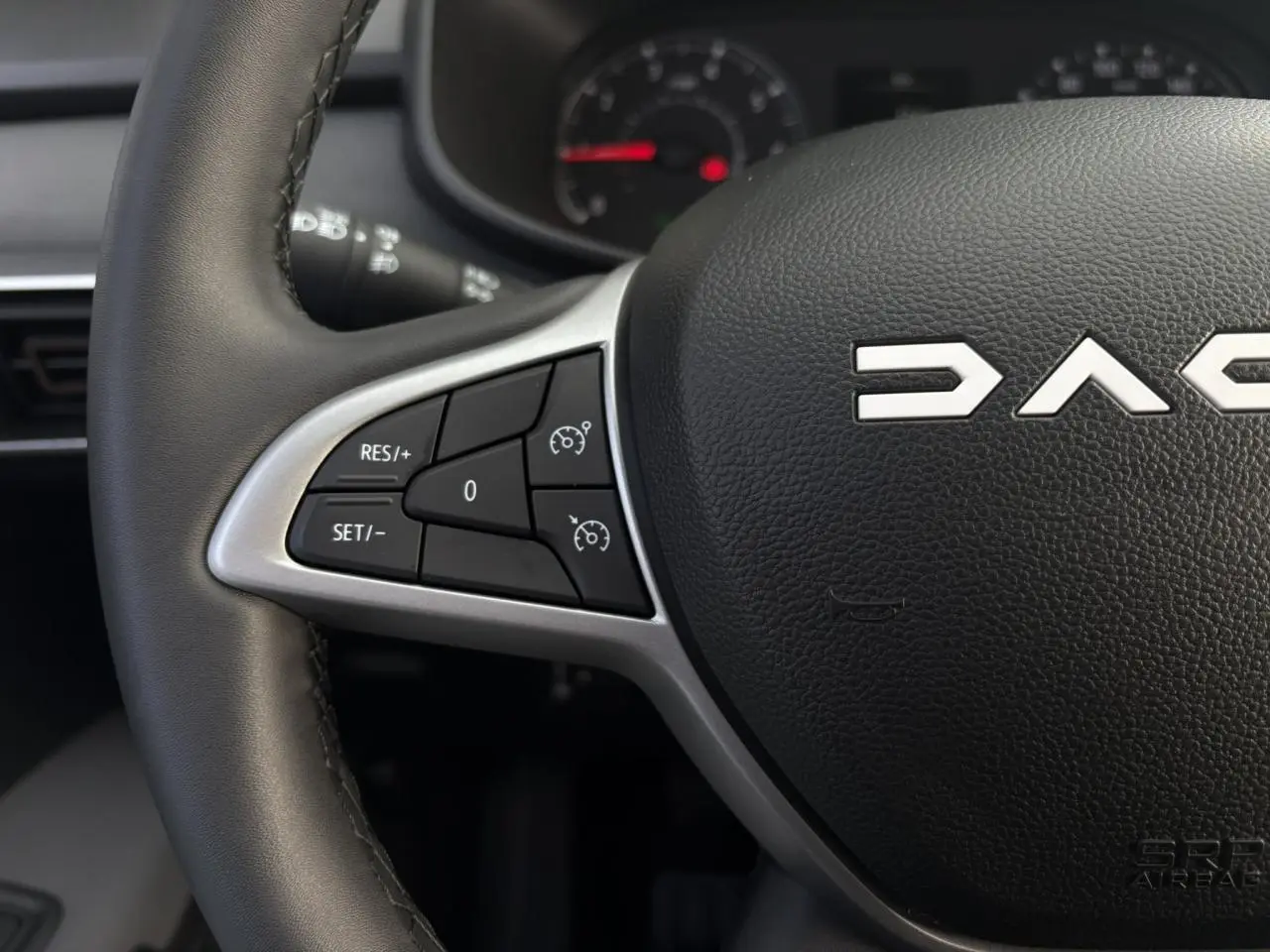 Gros plan sur le volant noir de la Dacia Jogger 2024 avec commandes de régulateur de vitesse à gauche.