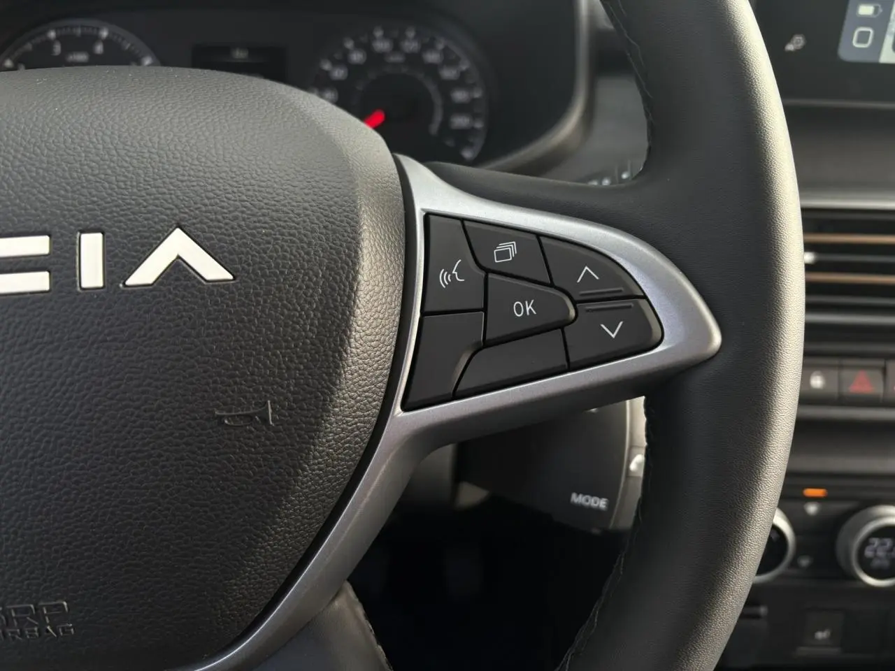 Gros plan sur le volant de la Dacia Jogger 2024, montrant les commandes multifonctions côté droit en plastique noir et argent.