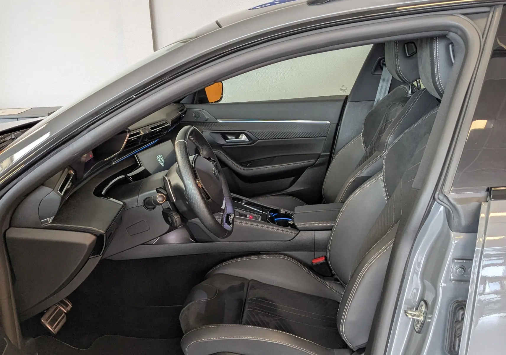 Intérieur côté conducteur du Peugeot 508 SW gris selenium 2024, sièges cuir noir et tableau de bord moderne.
