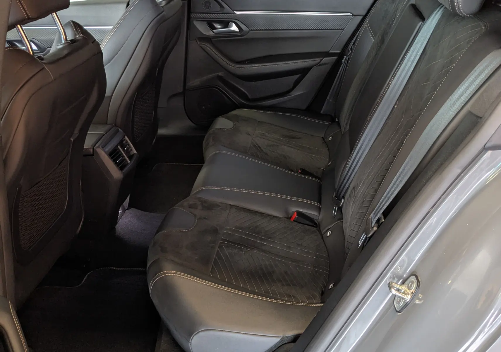Vue côté droit de l'intérieur arrière d'une Peugeot 508 SW gris selenium avec sièges cuir et alcantara noirs.