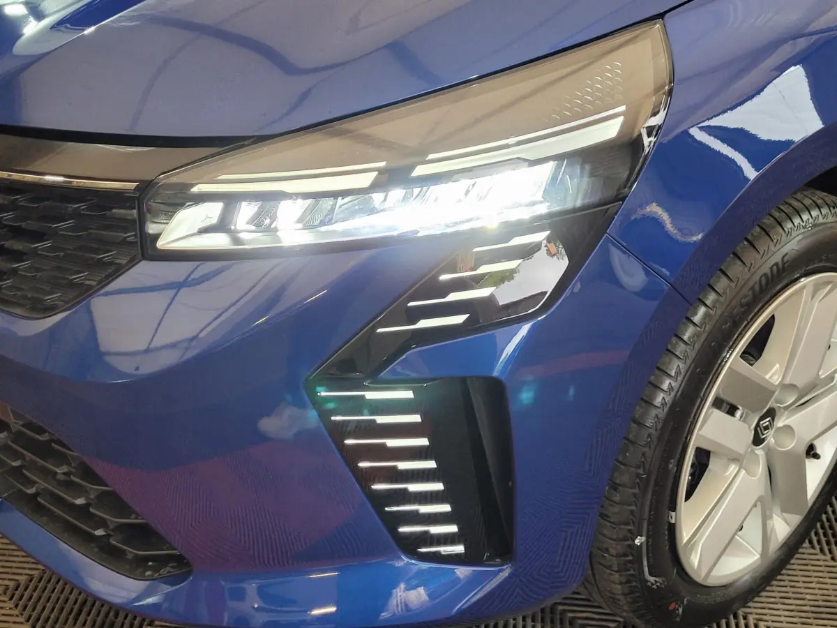 Gros plan sur l'avant droit de la Renault Clio bleu 2025, mettant en valeur ses phares LED et la jante argentée.