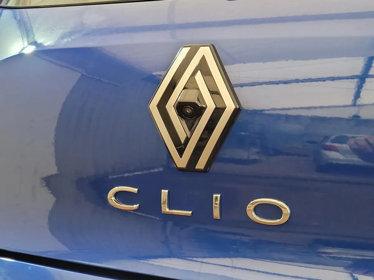 Gros plan sur le logo Renault et le nom Clio sur la malle arrière d'une Renault Clio bleu brillant.