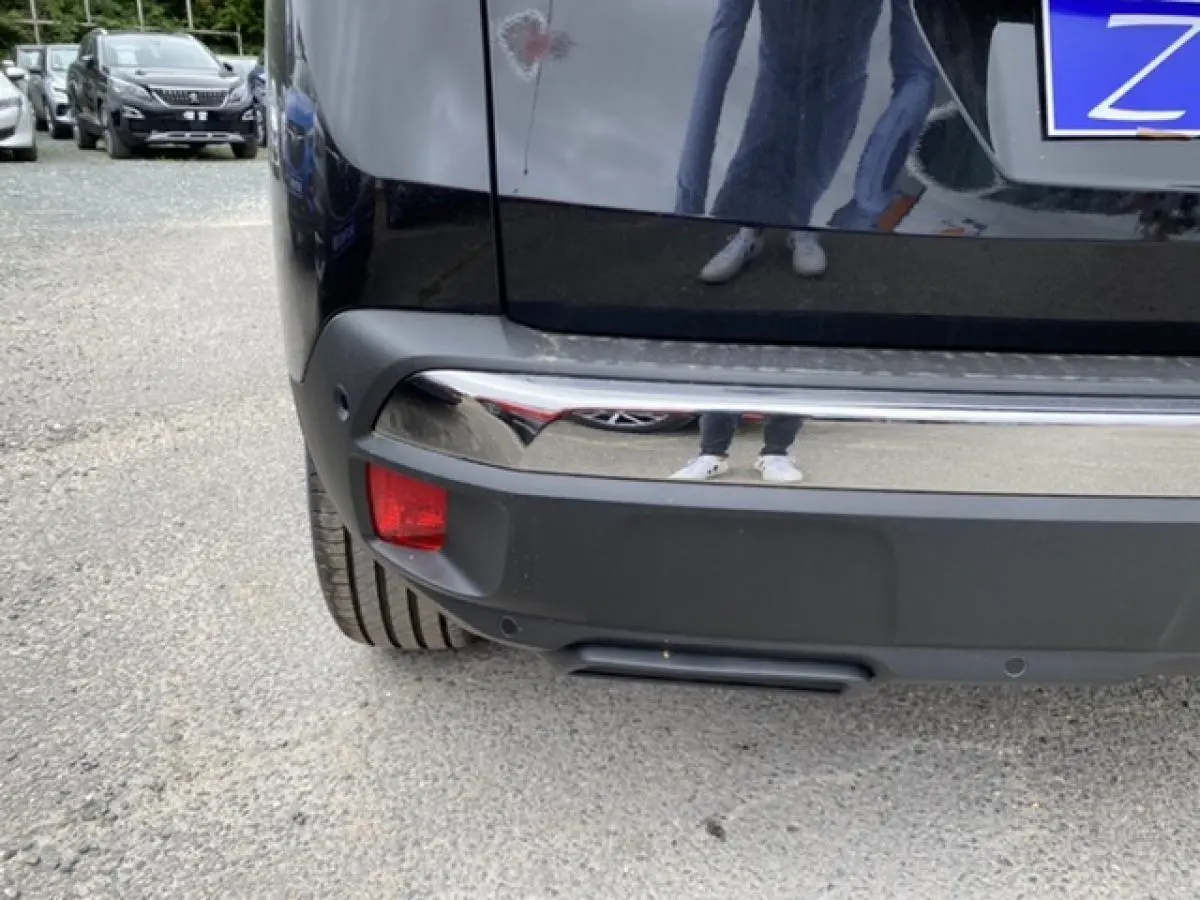 Gros plan sur le pare-chocs arrière noir perla nera du Peugeot 3008 2021, avec feu antibrouillard et capteurs de recul visibles.
