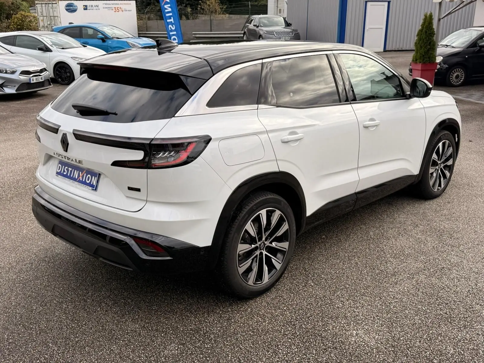 Vue 3/4 arrière droite du Renault Austral blanc nacré avec toit noir brillant et jantes alliage bicolores.