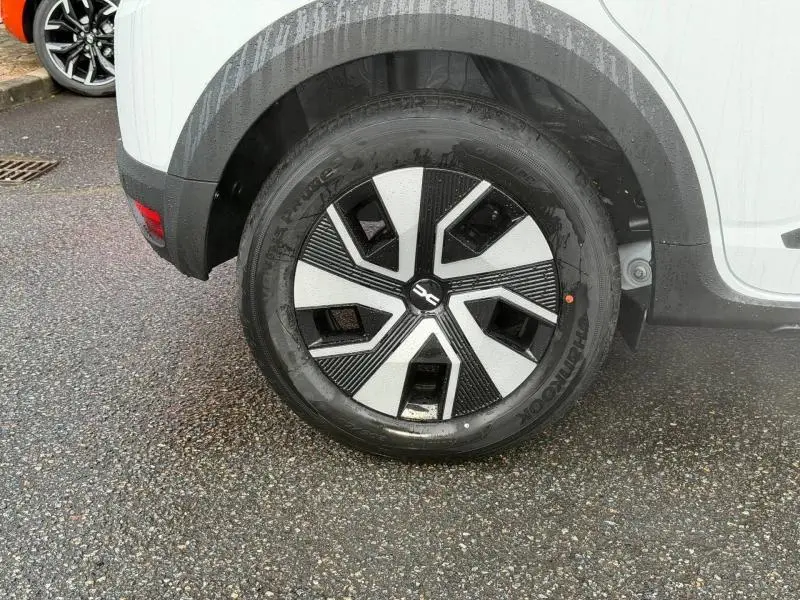 Gros plan sur la roue arrière droite d'une Dacia Sandero 2025 blanche avec jante au design géométrique bicolore.