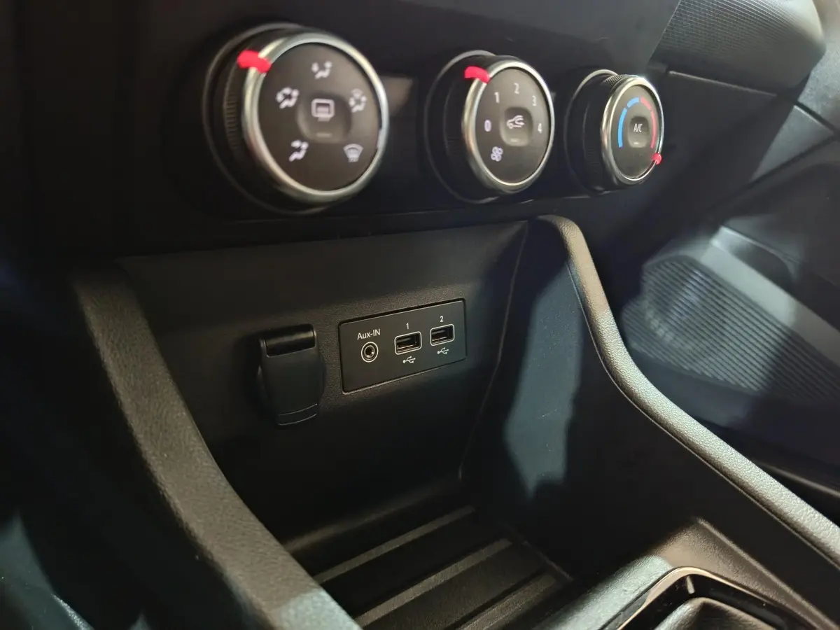 Gros plan sur les commandes de climatisation et les ports USB/Aux-In du tableau de bord de la Renault Clio gris clair 2023.