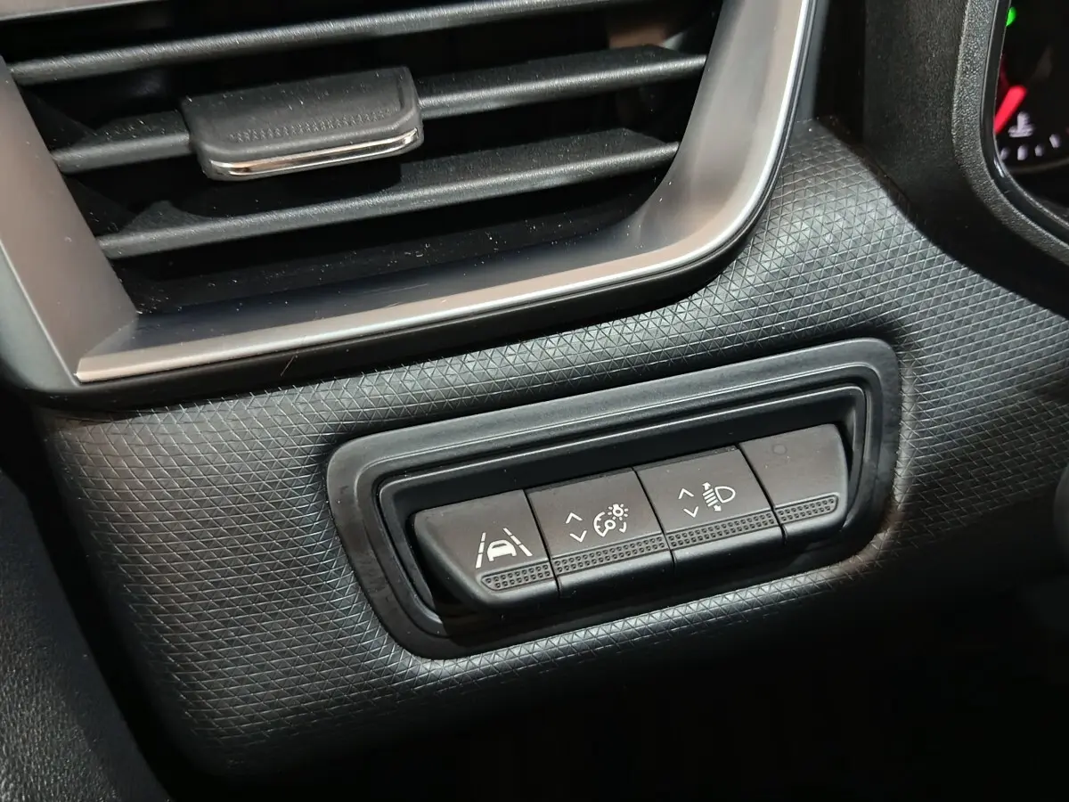 Gros plan sur les commandes d’aide à la conduite de la Renault Clio Equilibre TCe 90 2023, tableau de bord noir texturé.