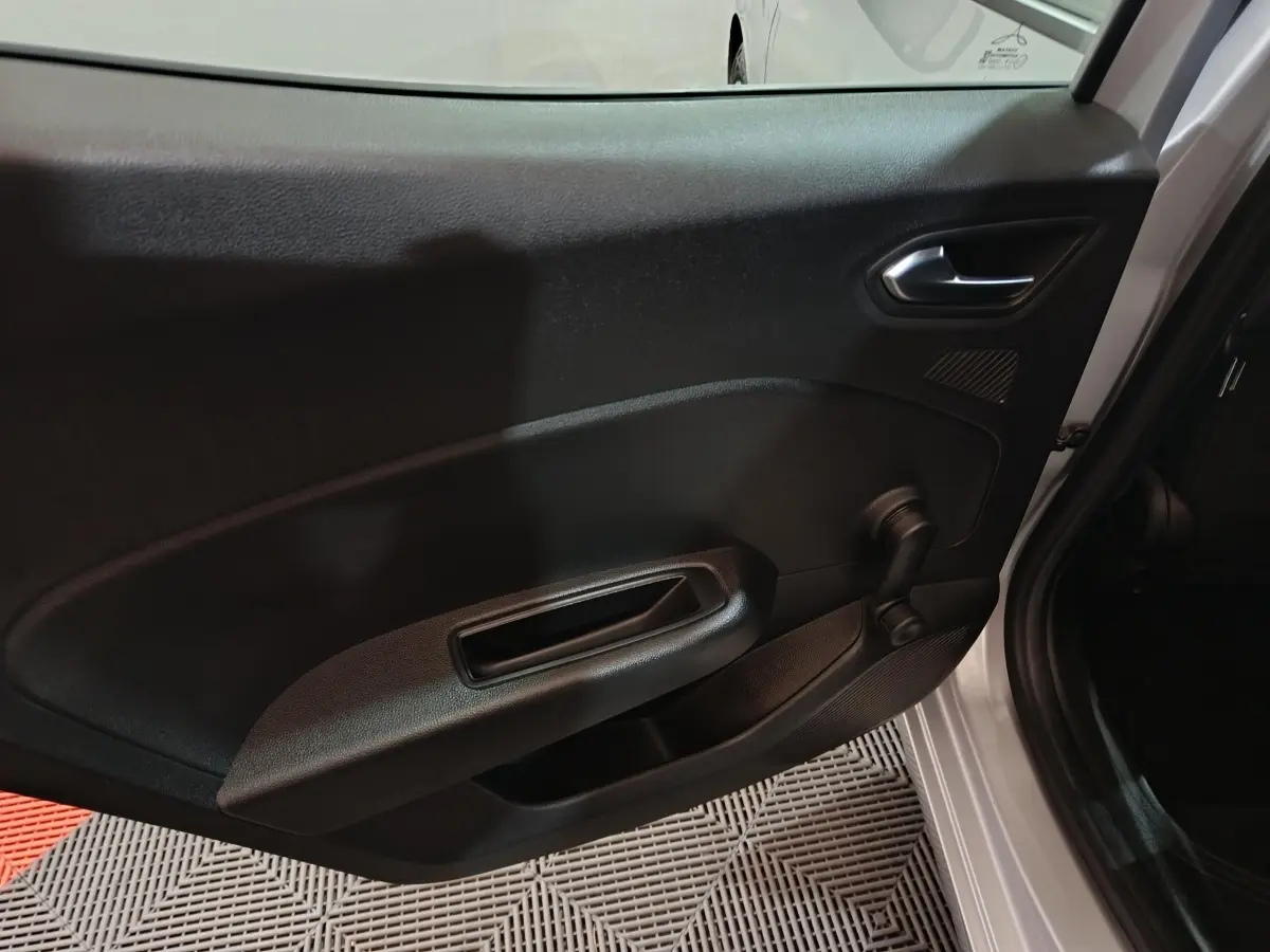 Vue intérieure côté gauche de la porte avant gris clair de la Renault Clio 2023 avec poignée manuelle de vitre.