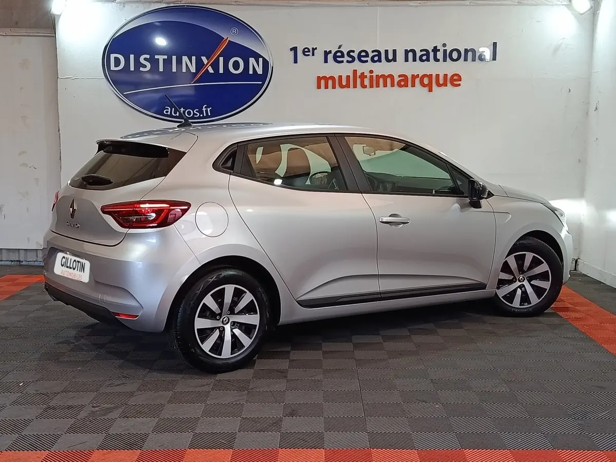 Profil droit d'une Renault Clio gris clair 2023 en version Equilibre TCe 90, avec jantes alliage et feux arrière LED visibles.