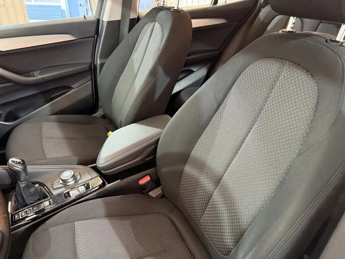 Vue intérieure rapprochée des sièges avant tissu gris et console centrale avec levier de vitesses manuelle d'une BMW X2.