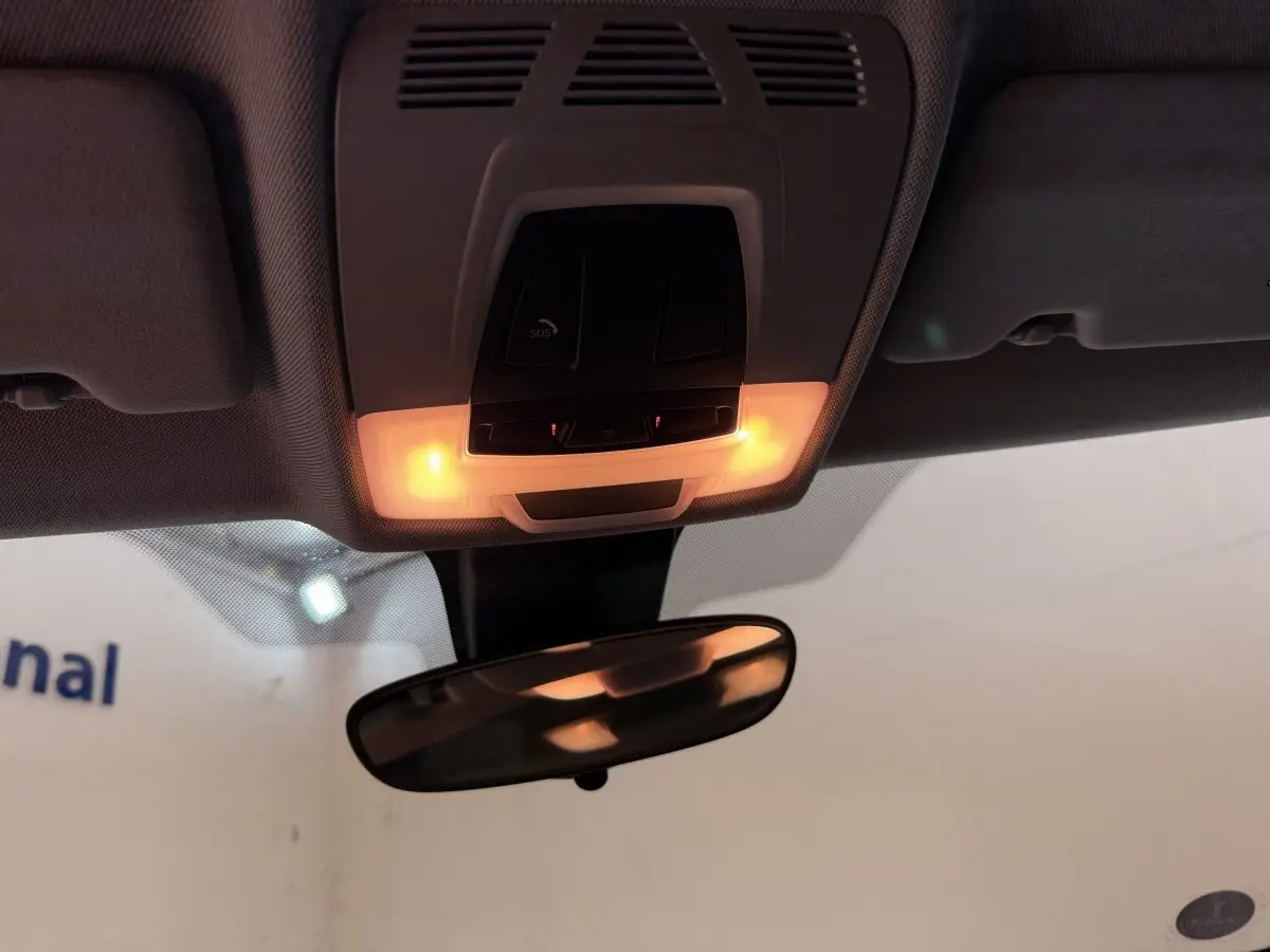 Vue intérieure du plafonnier avec éclairage orange et rétroviseur d'une BMW X2 blanche 2023.
