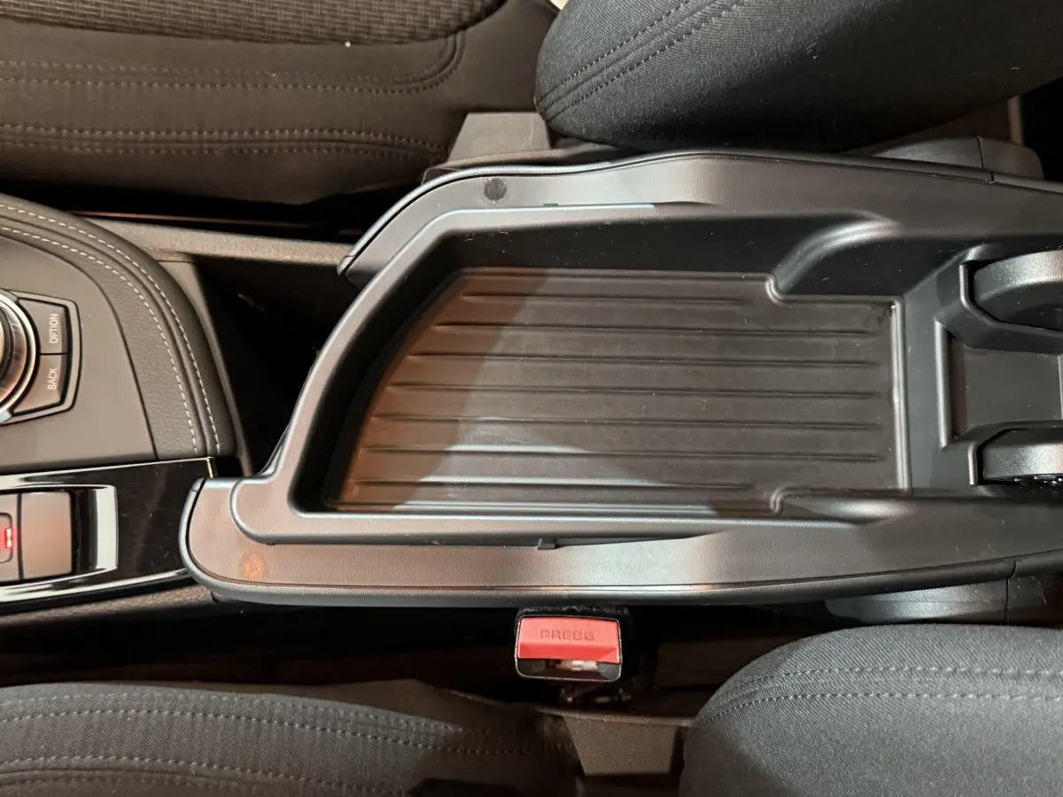 Vue rapprochée de la console centrale noire avec molette de sélection et accoudoir entre les sièges avant gris foncé du BMW X2 sDrive18i Lounge.