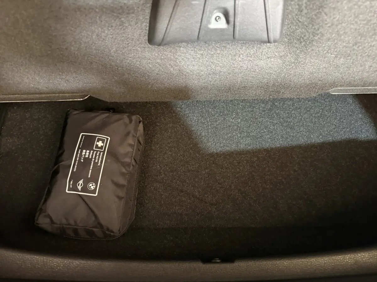 Gros plan sur le coffre noir intérieur d’une BMW X2 sDrive18i Lounge 2023 avec trousse de secours noire posée.