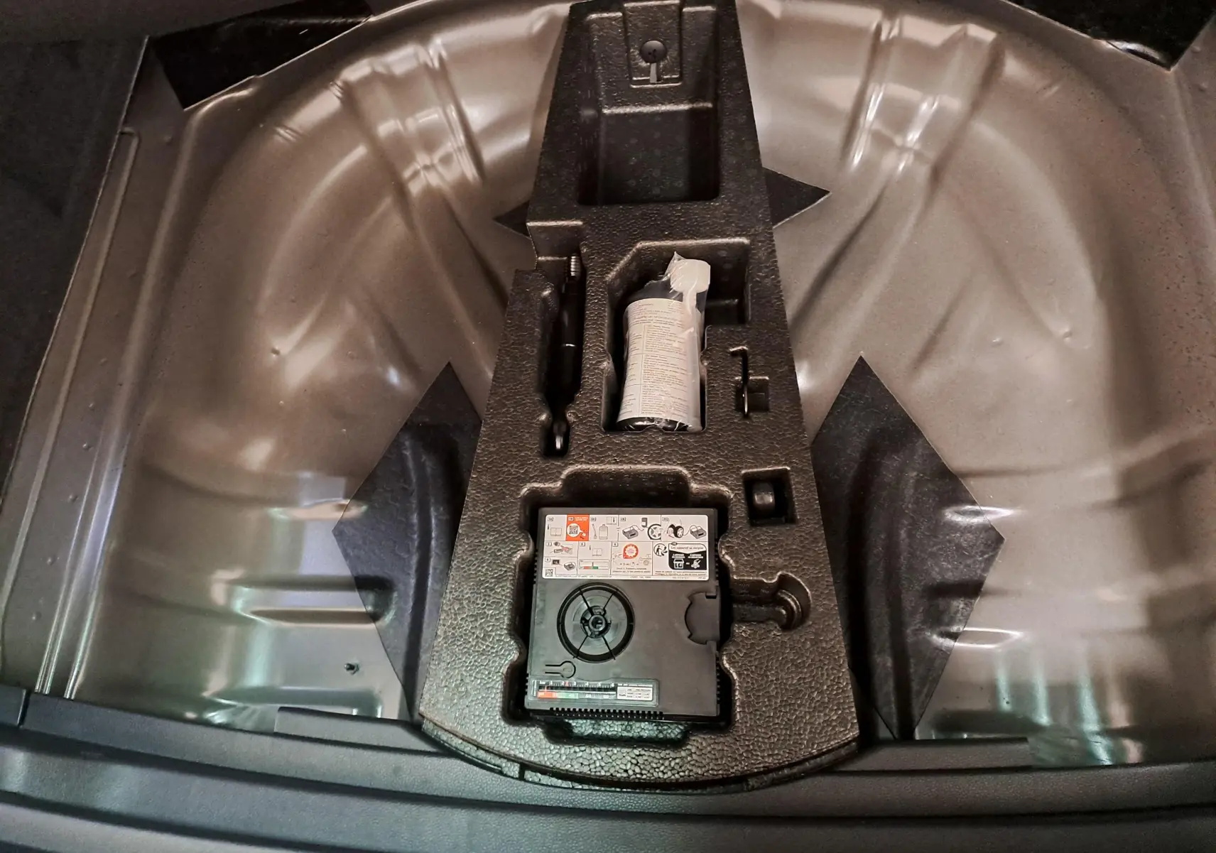Vue intérieure du coffre du CUPRA Ateca 2024 noir magique, montrant le rangement pour kit de réparation pneus.