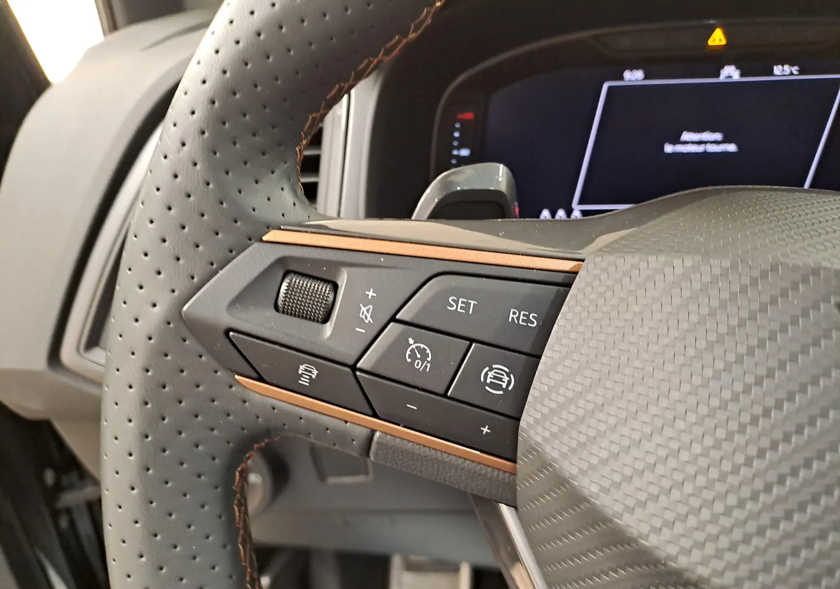 Gros plan sur les commandes du volant perforé du CUPRA Ateca 2024 noir magique, avec surpiqûres cuivrées et détails carbone.