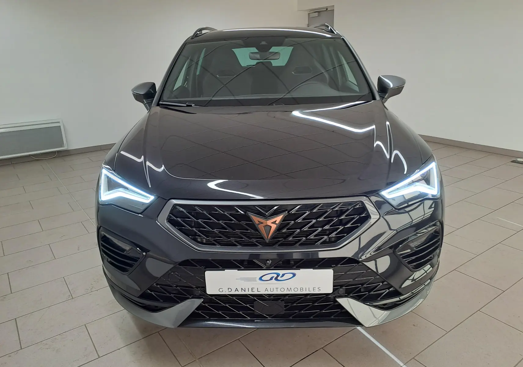 Vue avant du CUPRA Ateca 2024 noir magique avec phares LED allumés et calandre distinctive au logo cuivré.