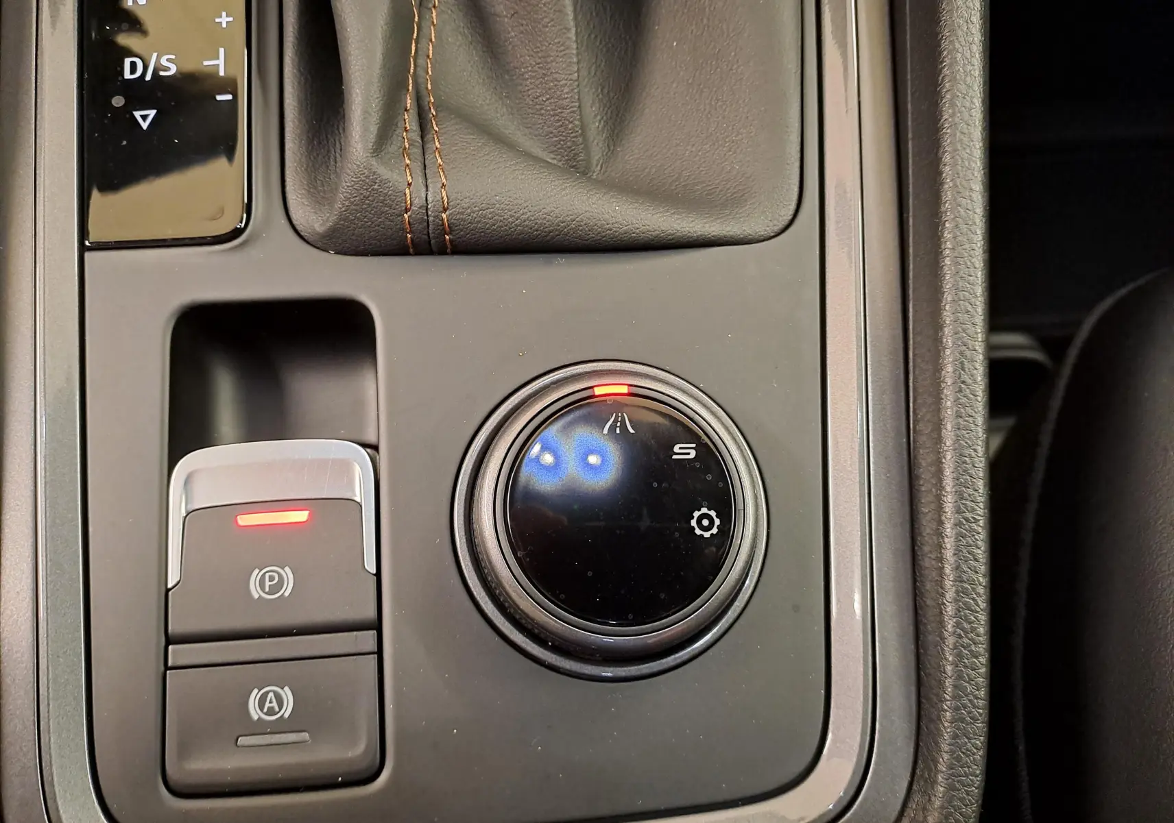 Gros plan sur la molette de sélection de mode de conduite et frein de parking électronique dans le coffre central d’une CUPRA Ateca noir magique 2024.