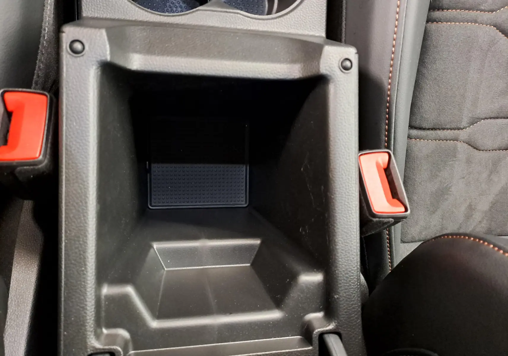 Vue plongeante sur le rangement central intérieur noir avec surpiqûres orange du CUPRA Ateca 2024 Noir Magique.