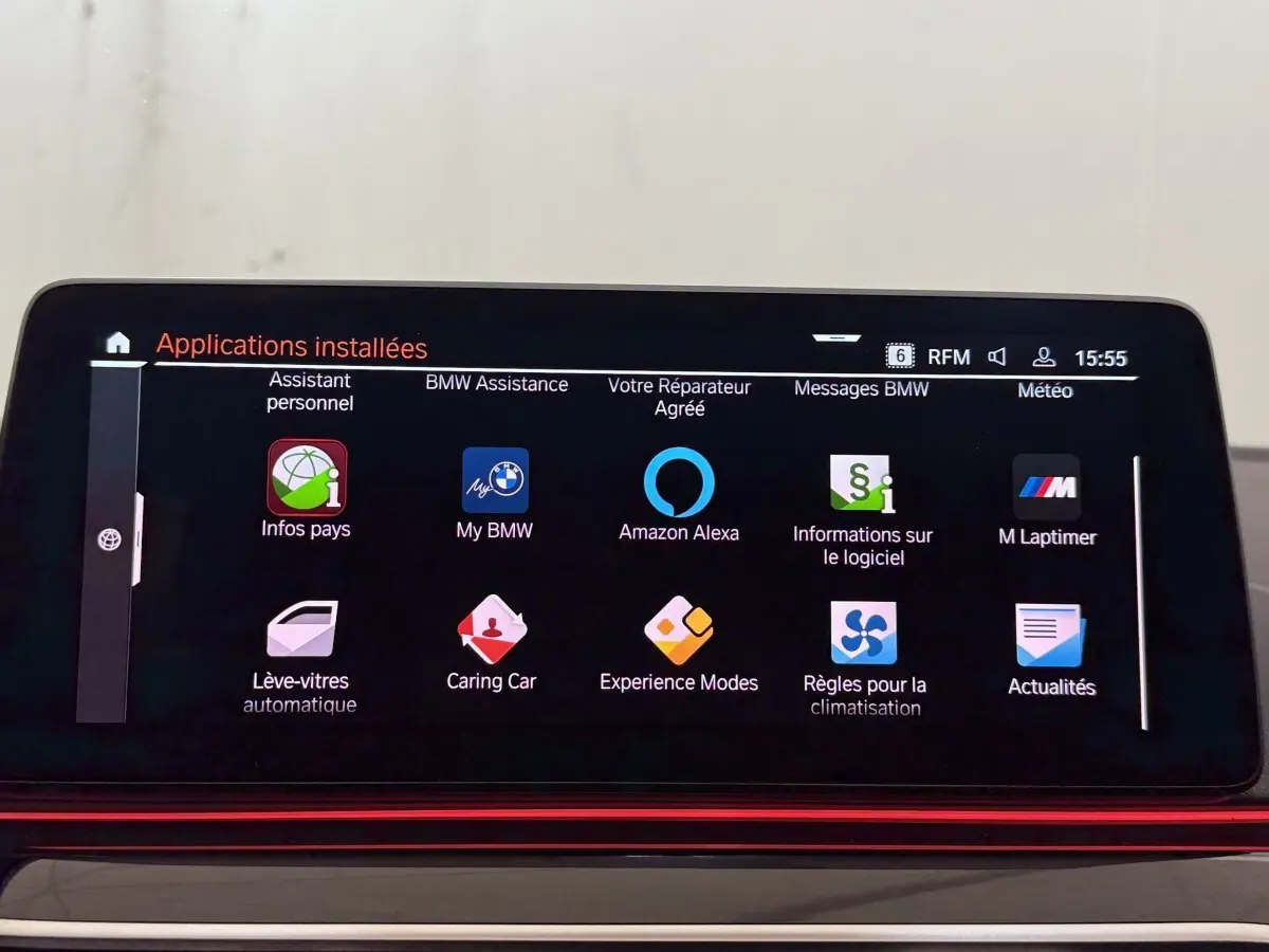 Écran tactile central affichant les applications connectées dans l’habitacle d’une BMW Série 5 Touring noire, vue de face.