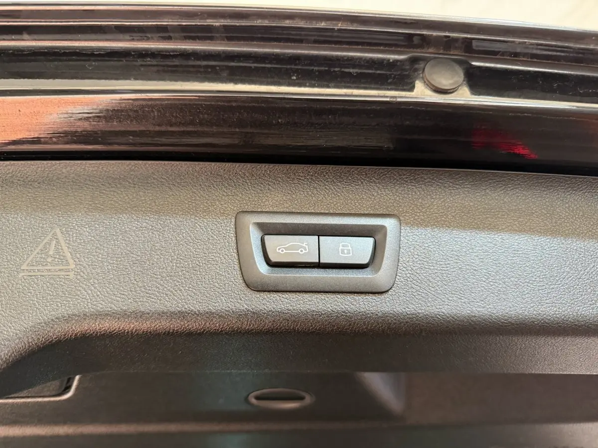 Gros plan sur les boutons de fermeture et verrouillage du coffre de la BMW Série 5 Touring noire, version 520d M Sport.