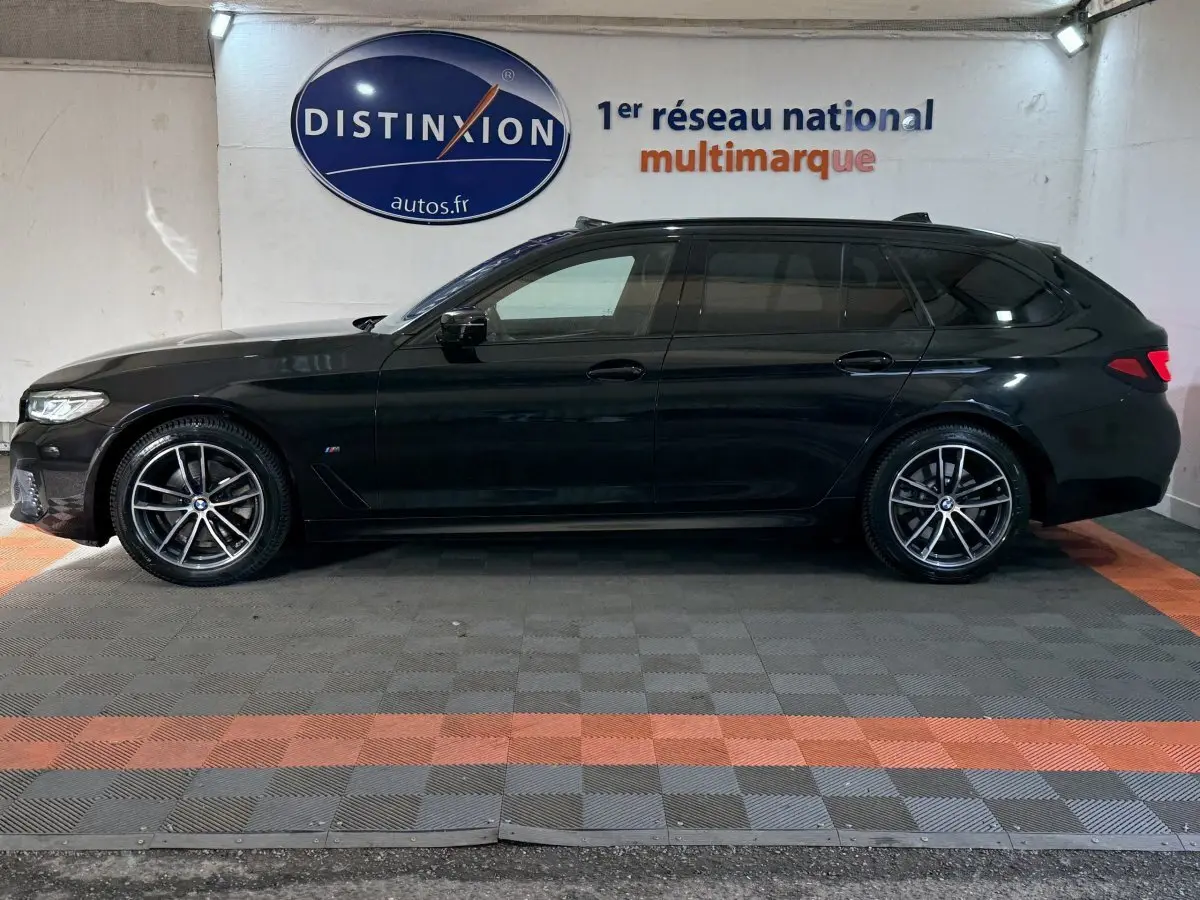 BMW Série 5 Touring 520d M Sport noire vue de profil côté gauche, avec jantes alliage et toit noir brillant.