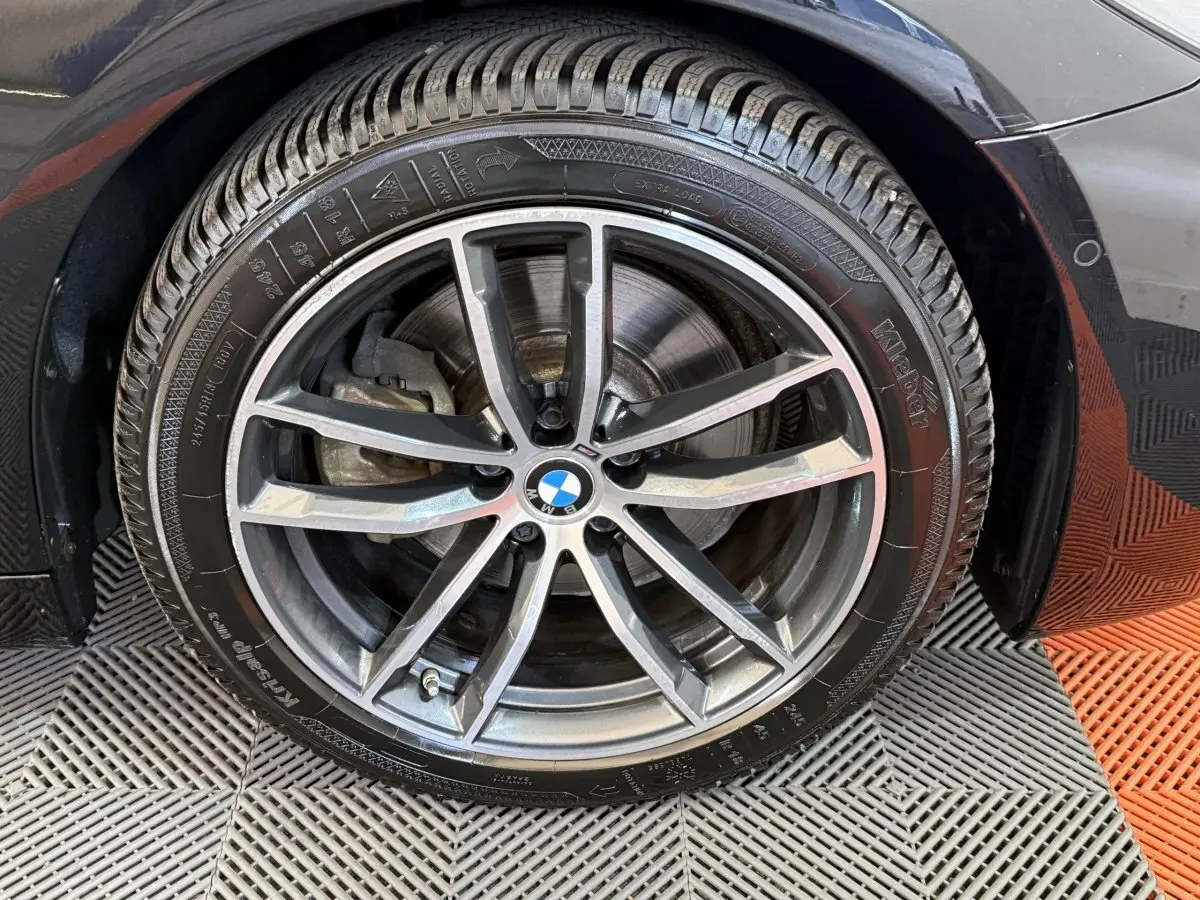 Gros plan sur la roue avant droite noire d’une BMW Série 5 Touring 520d M Sport avec jante alliage à 5 doubles branches.