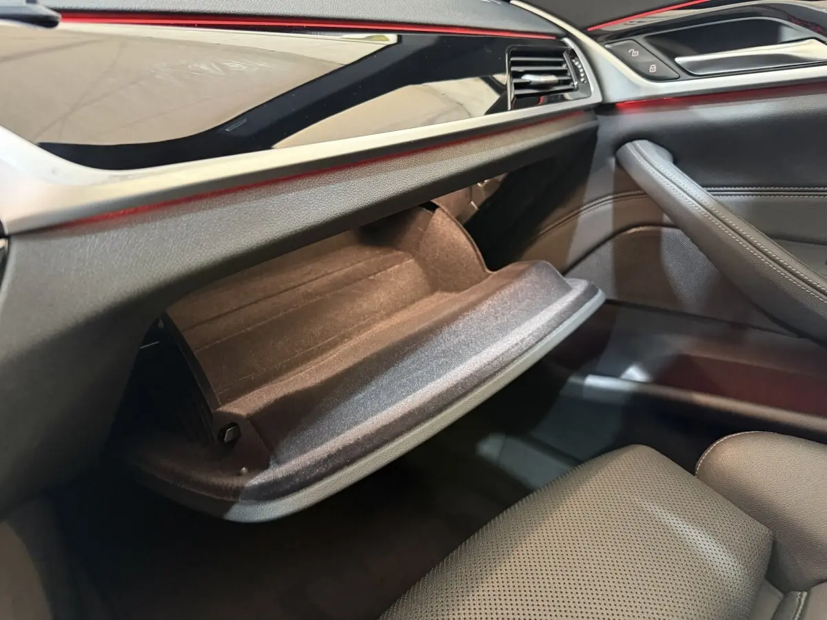Vue intérieure côté passager de la BMW Série 5 Touring 520d M Sport 2023, boîte à gants ouverte et garniture noire.
