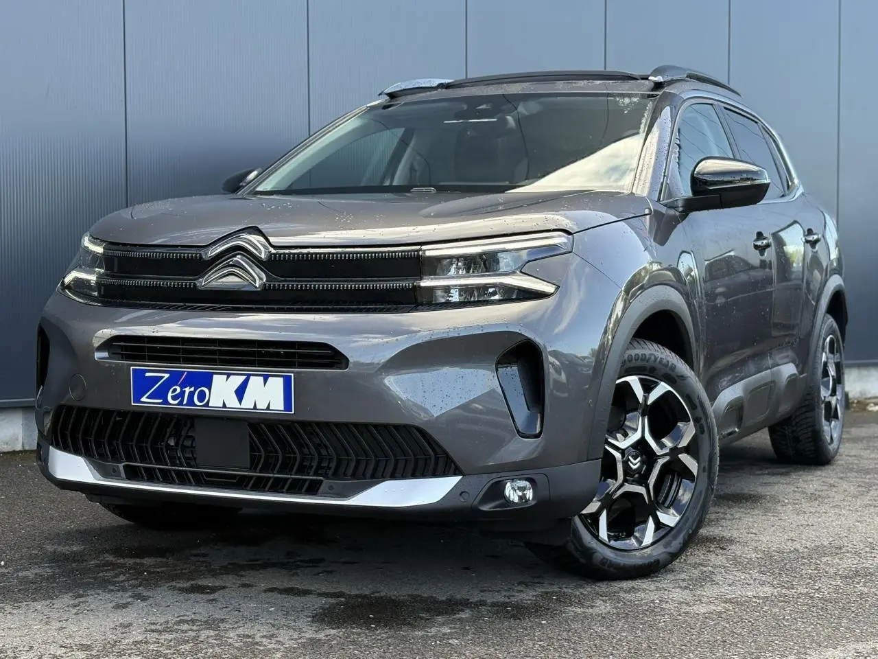 Citroën C5 Aircross gris Platinium en 3/4 avant droit avec jantes diamantées et toit ouvrant panoramique visible.