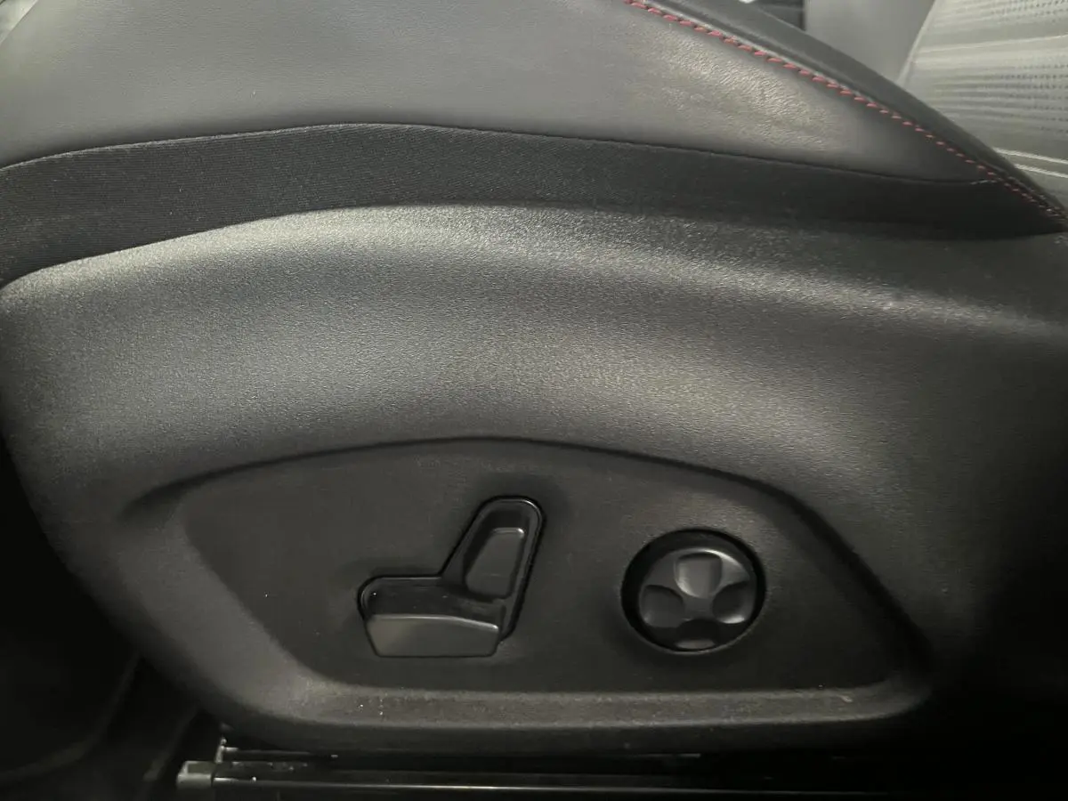 Détail des commandes de réglage électrique du siège avant en cuir noir avec surpiqûres rouges de l'Alfa Romeo Tonale 2024.