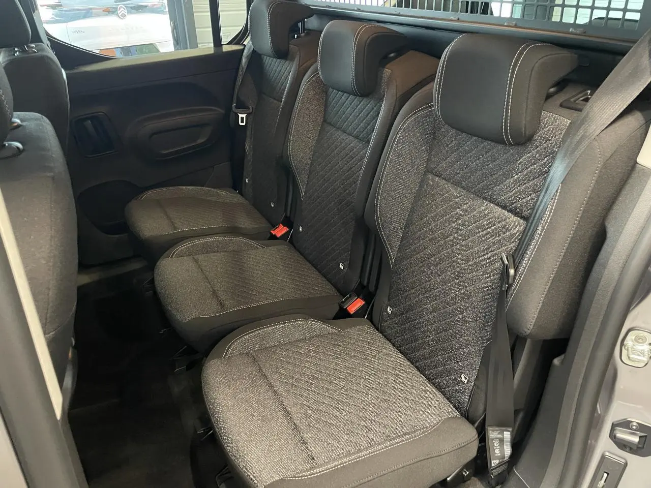 Vue intérieure sur la banquette arrière tissu Sixties gris du Peugeot Rifter 2026, avec portes coulissantes ouvertes.